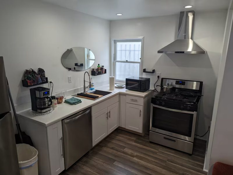 Kitchen with a gas range and extractor hood, full-size dishwasher, microwave and filter coffee maker.