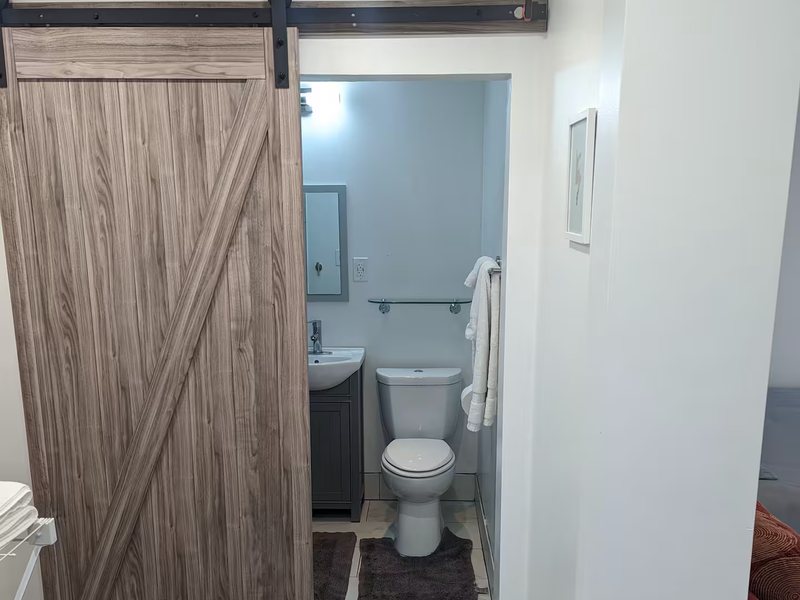 A sliding barn door opening onto the bathroom, with fresh towels on the shelving beside it.