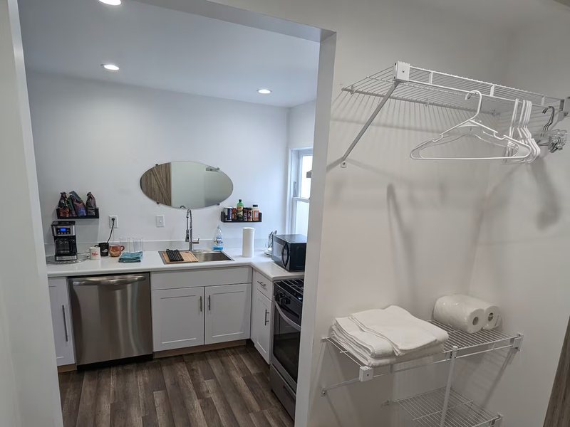 Looking through to the kitchen, with open hanging storage, towels and linens on the right.